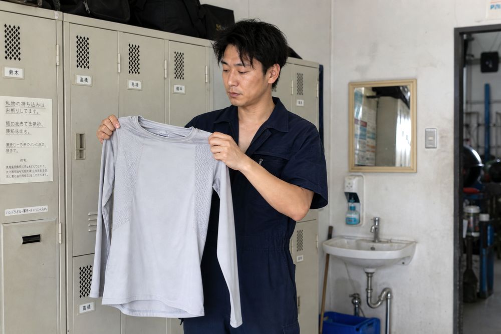 整備士がつなぎ服の下に冷感インナーを着用するイメージ